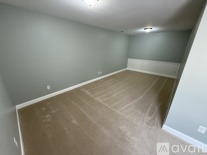 A room with a wooden floor and grey walls is available for rent.