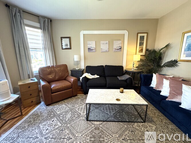 A living room with a brown leather chair, a black sofa, and a patterned rug.