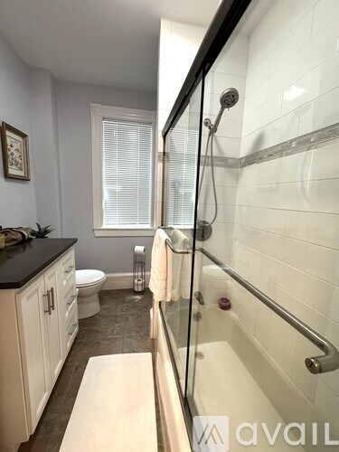 A bathroom with a glass shower door and a towel hanging on the shower rod.