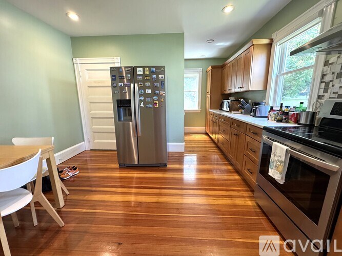 A kitchen with a wooden floor and a stainless steel refrigerator.