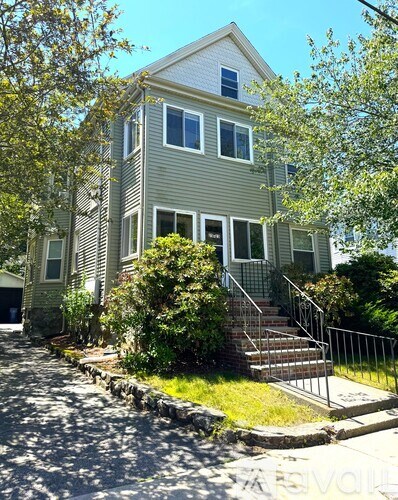 A house with a grey siding and a white roof with a small porch and a metal railing.