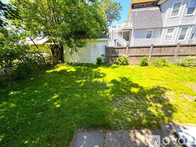 A backyard with a well-maintained lawn and a tree in the foreground.