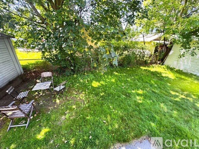 A backyard with a lawn, chairs, and trees.