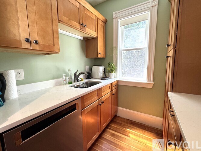 A kitchen with wooden cabinets and a stainless steel dishwasher.