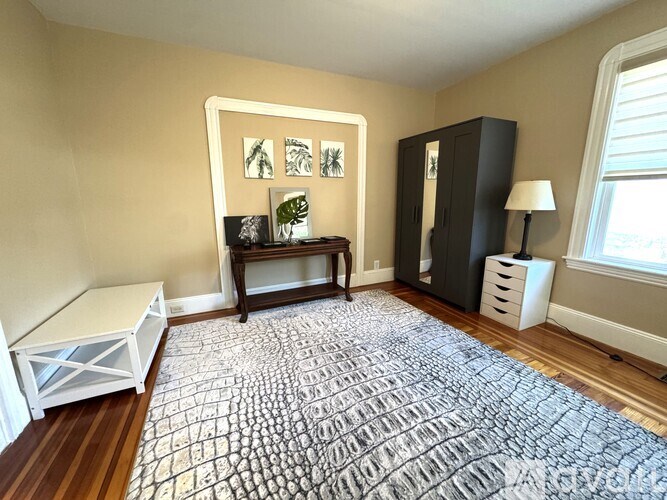 A room with a patterned carpet and a wooden floor.