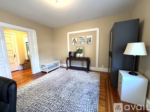 A living room with a grey rug and a black chair.