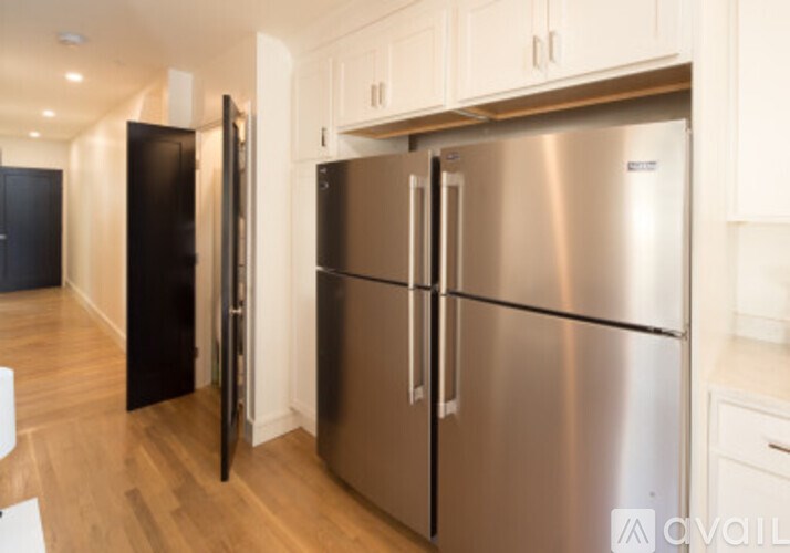 A stainless steel refrigerator in a kitchen with white cabinets.