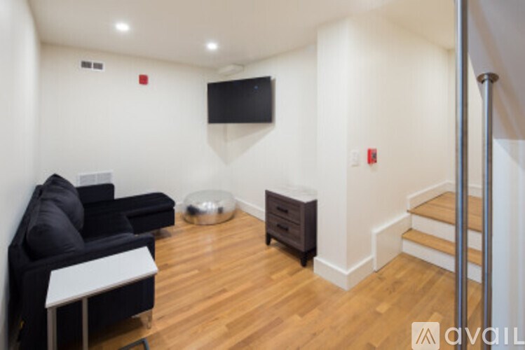 A living room with a black couch and a television on the wall.
