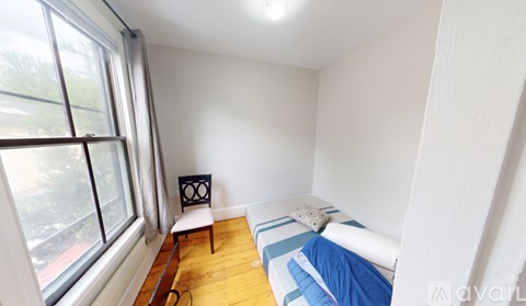 A small bedroom with a bed, chair, and window.