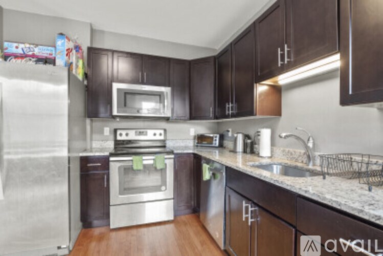 A kitchen with dark brown cabinets and a stainless steel refrigerator.