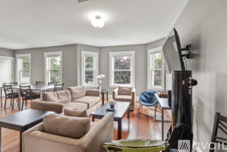 A living room with a couch, chairs, and a television.