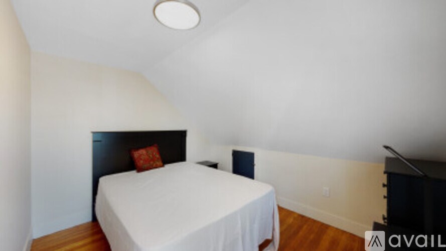 A bedroom with a bed, wooden floor, and a black headboard.