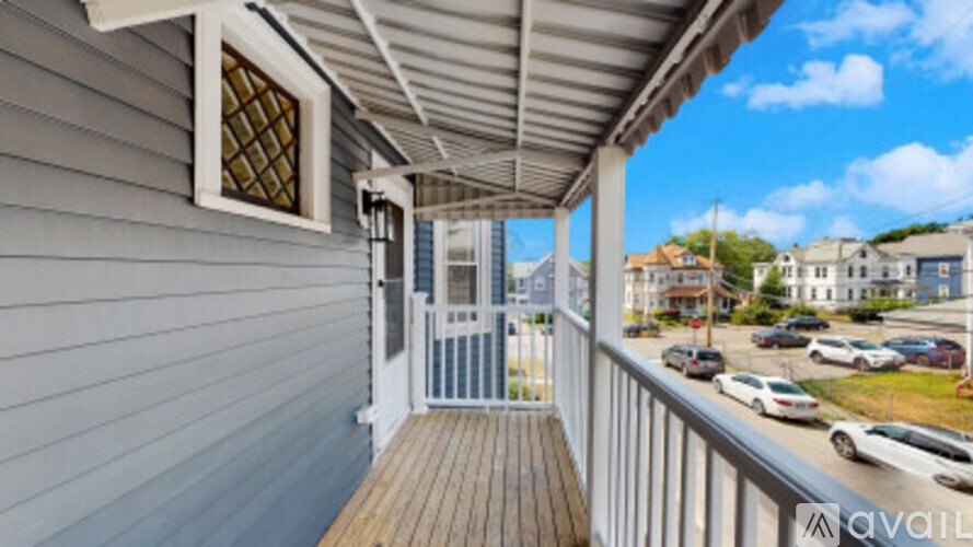 A balcony with a wooden floor and a metal railing overlooking a parking lot.