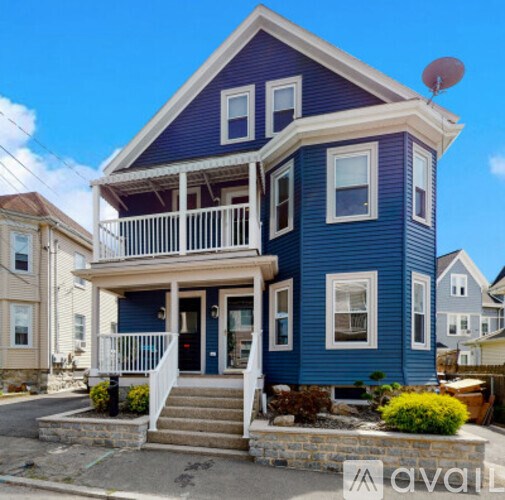 A blue house with a white porch and a satellite dish on the roof.