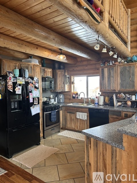 A kitchen with wooden cabinets and a black fridge.