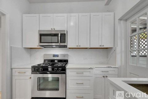 A kitchen with white cabinets and appliances.