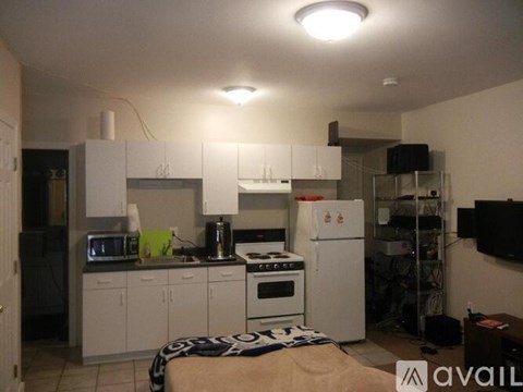 A kitchen with white cabinets and appliances, a refrigerator, and a stove top oven.
