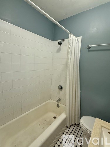 A room with a ceiling fan and light, hardwood floors, and a large window letting in natural light.