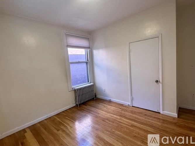 A room with wooden floors and a window with blinds.