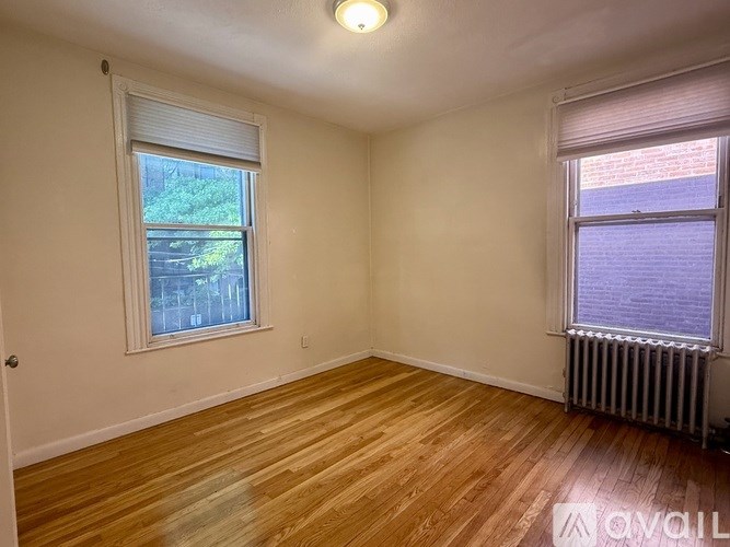A room with wooden floors and two windows.