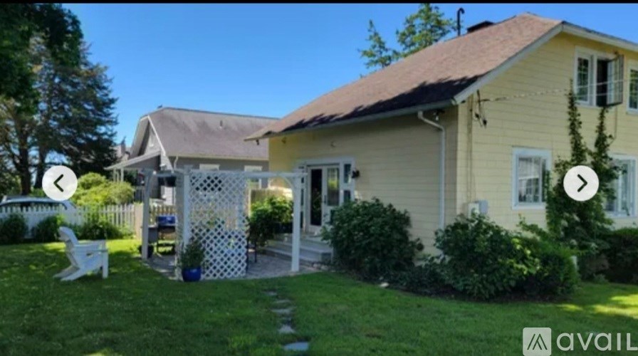 A yellow house with a white fence and a white chair in front of it.