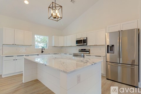 A kitchen with white cabinets and a marble countertop.