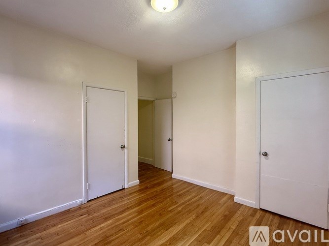 A modern kitchen with white cabinets and a wooden floor.