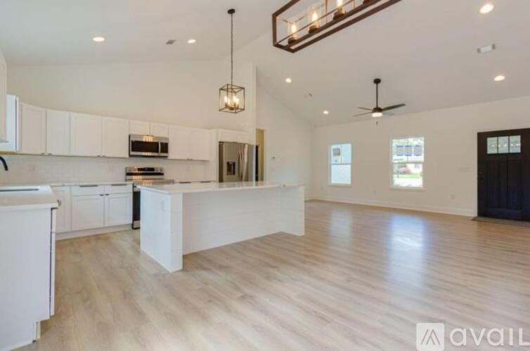 A spacious kitchen with white cabinets and a wooden floor.