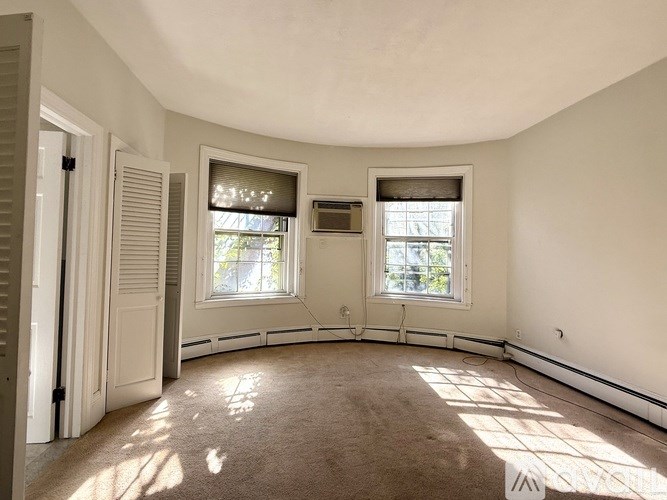 A room with a carpeted floor and two windows.