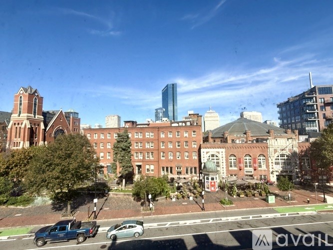 A city street with a blue truck and a white car driving down the road.