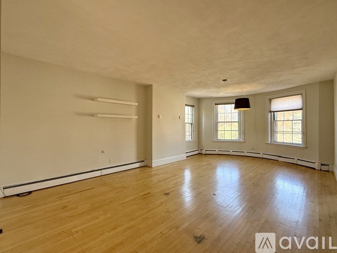A room with wooden floors and two windows, one of which is open.