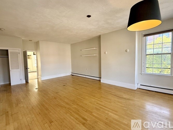 A room with wooden flooring and a large window.