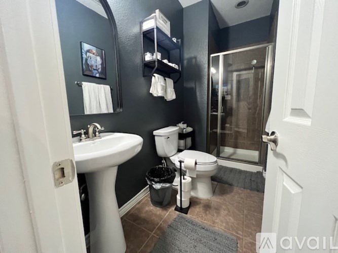 A bathroom with a white pedestal sink, toilet, and a glass shower door.