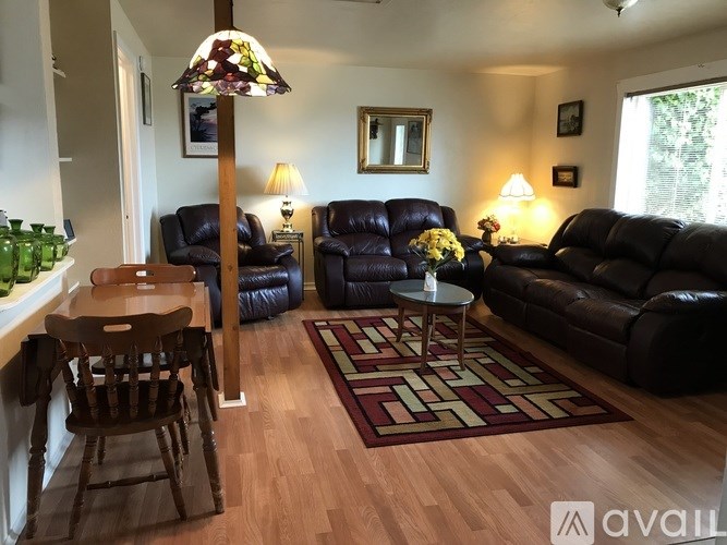 A living room with a brown leather couch and a wooden table.