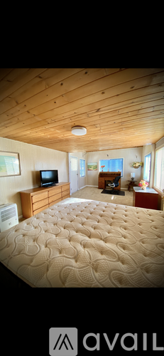 A bedroom with a large bed and a wooden ceiling.