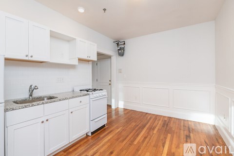 A kitchen with white cabinets and a wooden floor.