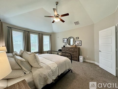 A bedroom with a large bed and a ceiling fan.