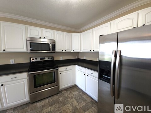 A kitchen with white cabinets and a stainless steel refrigerator.