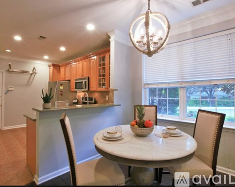 A kitchen with a table set for two with a bowl of fruit on it.