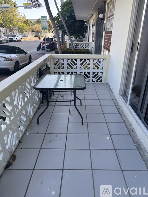 A balcony with a table and chairs overlooking a street.
