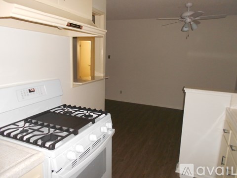 A white stove in a kitchen with a fan in the room.