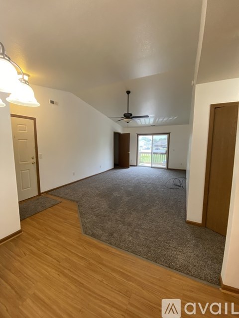 A room with a ceiling fan and a door leading to a balcony.