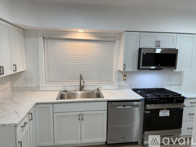 A kitchen with white cabinets and a black microwave.