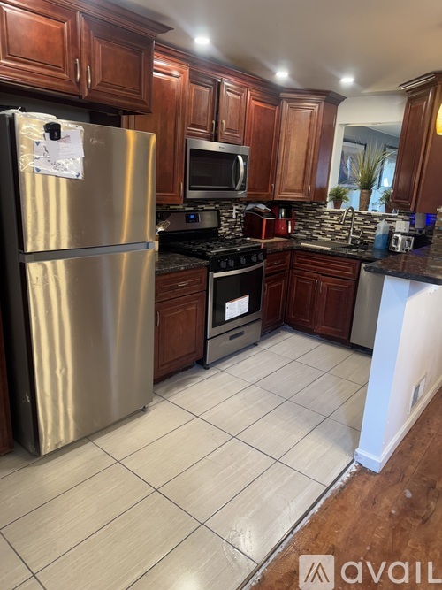 A kitchen with a stainless steel refrigerator and wooden cabinets.
