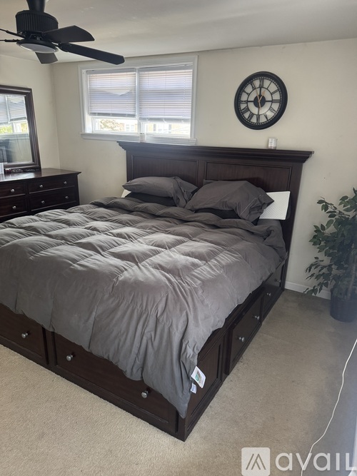 A bedroom with a bed, dresser, and window.
