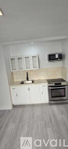 A kitchen with white cabinets and a microwave above the stove.