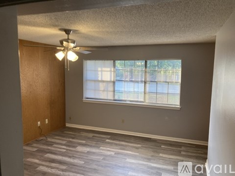 A room with a ceiling fan and a window with blinds.