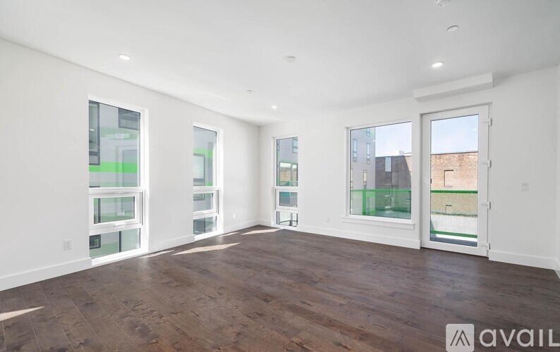 A spacious room with wooden floors and large windows.