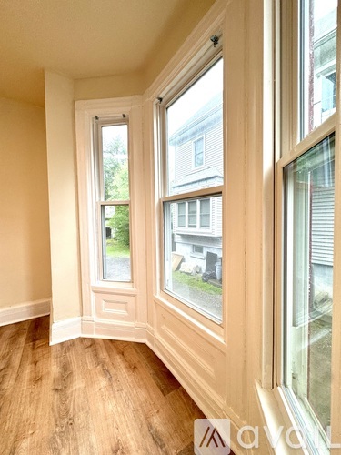 A room with a window showing a view of a house across the street.