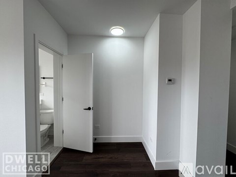A white door is open to a bathroom in a white room.